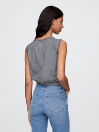 Sort og hvidt ternet sansærmet top med flæser på skuldrene, parret med højtaljede blå denim jeans med baglommer.