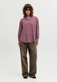 Rutet skjorte i pink og hvid med knappet forside, kombineret med brede brune bukser. Skjorten har lange ærmer og en afslappet pasform.