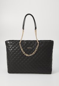 Sac tote noir matelassé en matériau synthétique, dot�é de deux poignées noires et d'une accentuation en chaîne dorée. Logo affiché de manière proéminente sur le devant.
