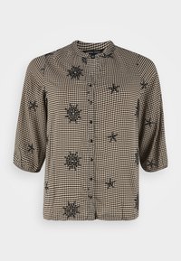 Chemise vichy noire et blanche avec des manches trois-quarts, boutonnage à l'avant et accents de broderie florale noire. Tissu léger et texturé.