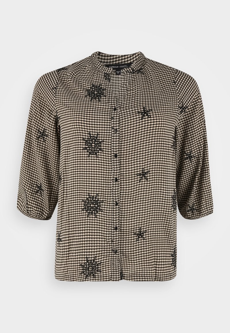 Chemise vichy noire et blanche avec des manches trois-quarts, boutonnage à l'avant et accents de broderie florale noire. Tissu léger et texturé.