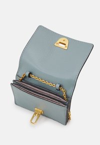 Světle modrá kožená peněženka s texturovaným povrchem, zlatým kováním, řetízkem a několika sloty na karty. Má uzávěr na přezku.