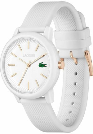 Baltas silikoninis laikrodis su tekstūruotu dirželiu, turintis apvalią ciferblatą, auksinius žymeklius ir žalią Lacoste logotipą.