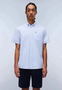 Short-sleeve button-up shirt in light blue with thin white stripes, featuring a chest pocket and small logo accent. Smooth cotton fabric.