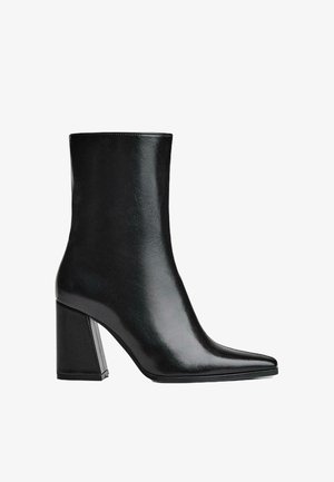 Fekete bőrből készült bokacsizma hegyes orral és magas tömb sarkal. Simára csiszolt textúra, letisztult sziluett és masszív alapforma jellemzi.