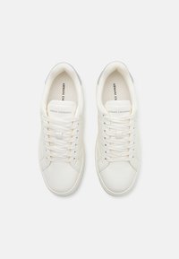 White leather sneakers with a smooth texture, featuring flat laces, a grey accent on the heel, and an embossed logo on the tongue.