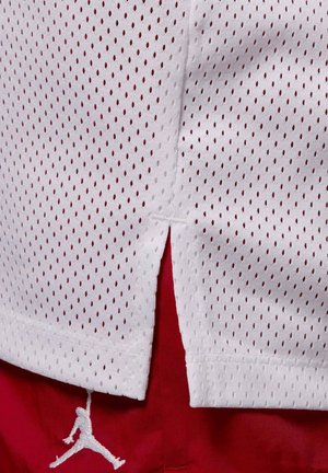 Biały materiał siateczkowy z małymi owalnymi otworami nakłada się na czerwony materiał z naszytą sylwetką skaczącego koszykarza.