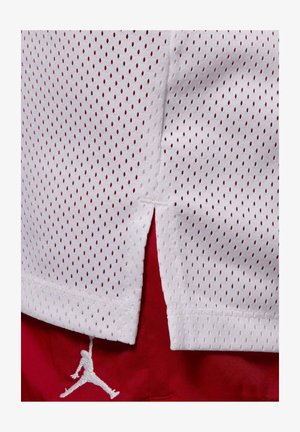 Tissu en mesh blanc avec de petits trous ovales superposé à un tissu rouge présentant une silhouette cousue d'un joueur de basket sautant.