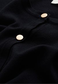 Svart stickad cardigan med en mjuk textur, rund halsringning och två guldfärgade knappar längs fronten.