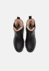 Černé kožené kotníkové boty s měkkou světle hnědou kožešinovou výstelkou, bočními zipy a zaoblenými špičkami. Hladký povrch je doplněn minimálním kováním.