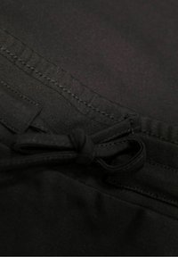 Černá látka s hladkým povrchem, která má prošívané švy a šňůrku v pase pro úpravu.