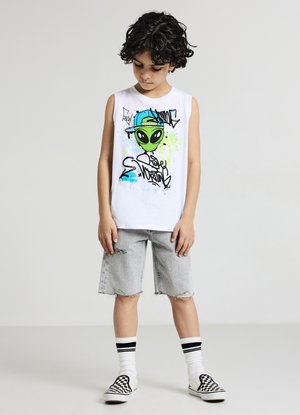 White sleeveless t-shirt with green alien graphic and graffiti design, paired with distressed denim shorts. Black and white checkered slip-ons.