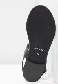 Semelle de sandale en cuir noir, design plat avec une texture lisse. Inscription "MADE IN ITALY" et taille "37" imprimées en blanc.