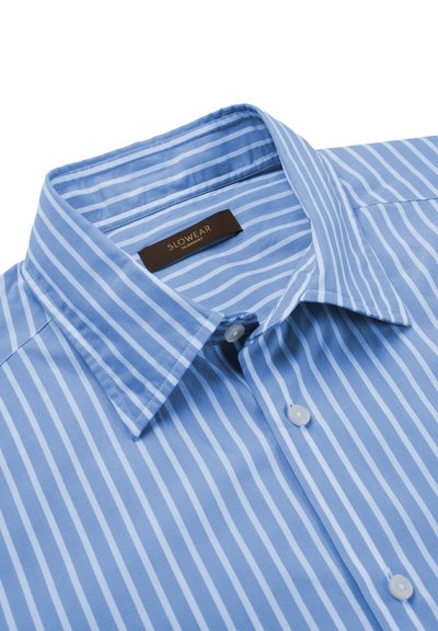 Niebiesko-biała koszula w pionowe paski, z kołnierzykiem, białymi guzikami oraz metką marki "SLOWEAR" wszytą wewnątrz kołnierza.