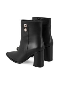 Zwarte leren enkellaarsjes met een puntige neus, stevige hakken en twee decoratieve knoppen aan de buitenkant. Gladde textuur, strak design.