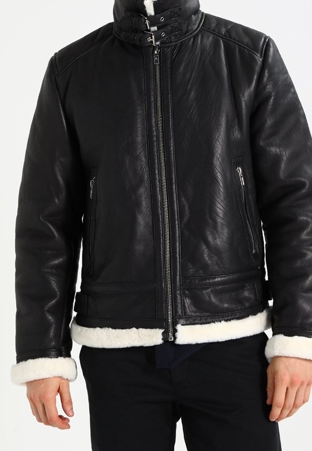 Veste en cuir noir avec un col haut, fermeture éclair et doublure en shearling. Caractéristiques de deux poches avant zippées et d'une finition texturée.