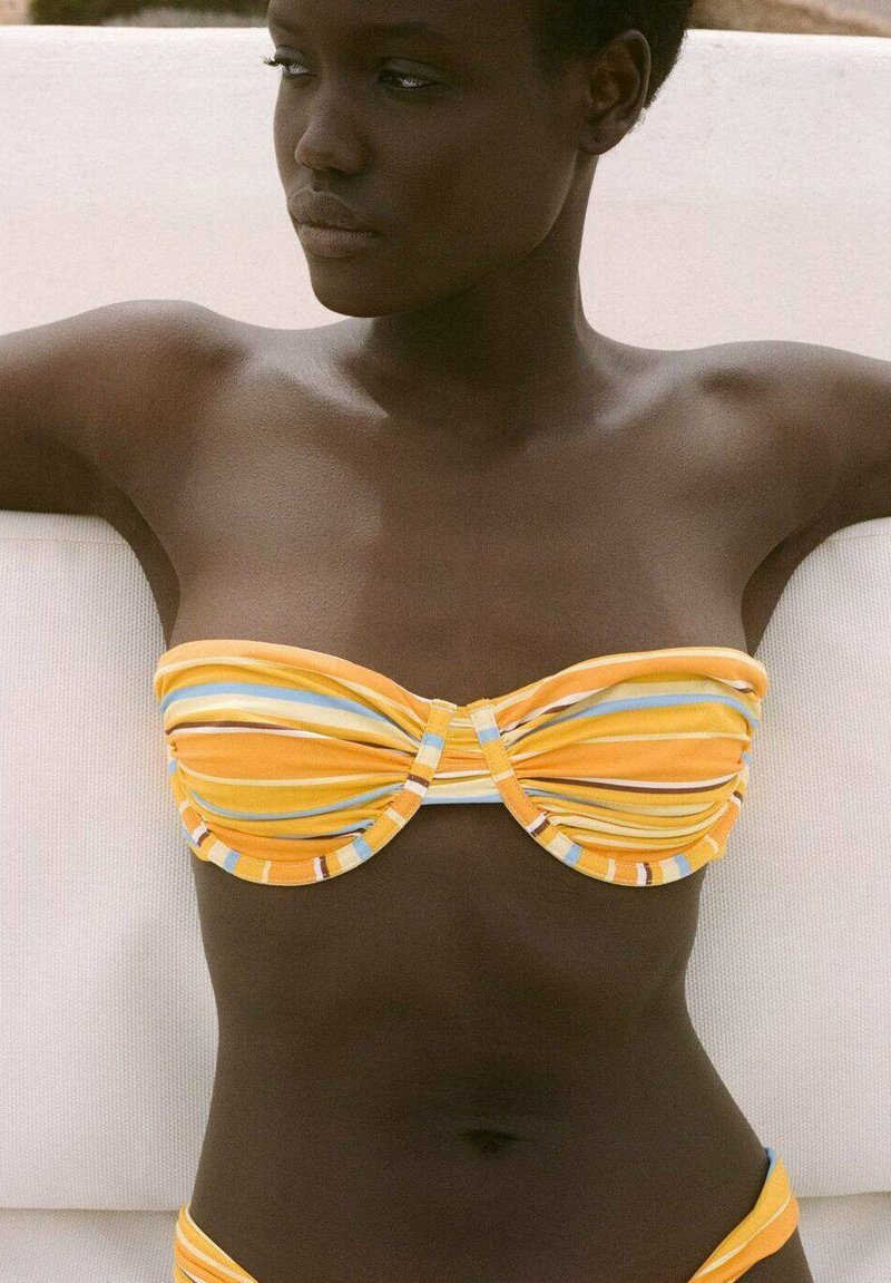 Bikini top bandeau z rumenimi in modrimi črtami, z gubanjem in osrednjim zasukom. Gladek material s kontrastnimi obrobami.