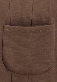 Tessuto marrone con un motivo texture, dotato di una grande tasca rotonda e dettagli di cuciture dritte. Materiale morbido con una leggera lucentezza.