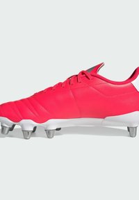 Scarpa da calcio sintetica rossa con tomaia testurizzata, caratterizzata da cuciture visibili e un accento sul tallone bianco. Dotata di tacchetti in metallo argentato per la trazione.