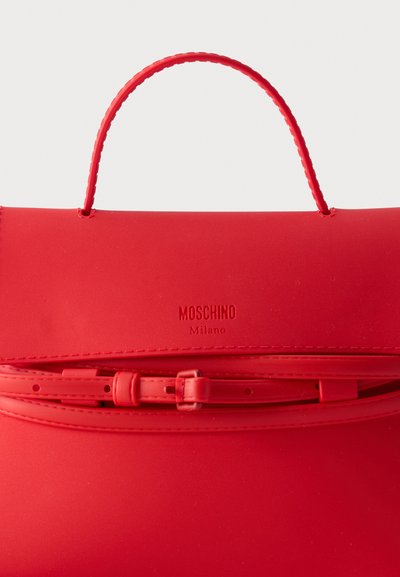 Κόκκινη τσάντα Moschino με επάνω χειρολαβή, ανάγλυφο λογότυπο και ρυθμιζόμενο λουράκι με αγκράφα στην μπροστινή κλείστρα.