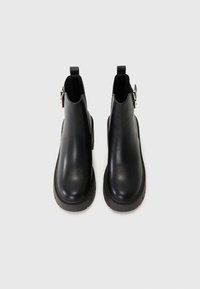 Sorte lær ankle boots med en glat tekstur, rund tå, elastiske sidelapper og en lille spænde på den ydre side.