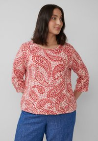 Rotes und pinkfarbenes Oberteil mit Mustern, drei Viertelärmel und rundem Halsausschnitt, aus leichtem Stoff mit glatter Textur.