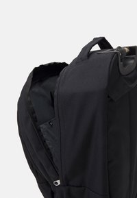 Schwarzer Rucksack aus strapazierfähigem Stoff mit einem Reißverschluss, ausgestattet mit einem Griff und einem glatten, strukturierten Innenfutter.