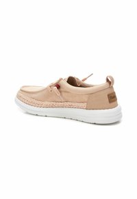 Botte en toile beige clair avec des détails tressés, semelle plate en caoutchouc blanc et lame arrière. Présente un accent en cordage et des lacets de traction.