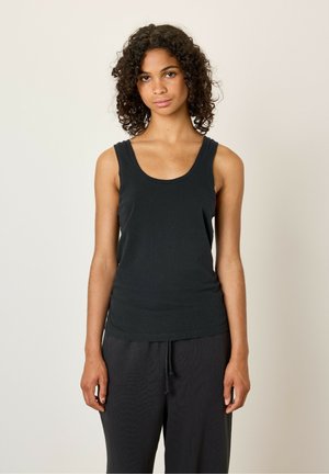 Black sleeveless tank top made from soft, lightweight fabric with a rounded neck and fitted design, paired with loose dark pants.
