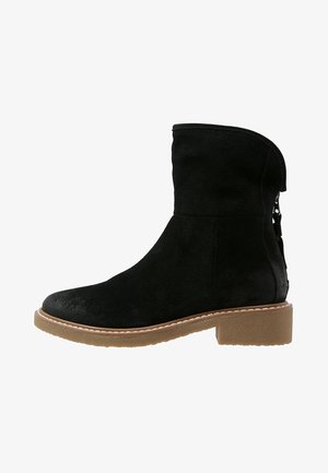 Black suede ankle boot with rounded toe, tan low block heel, and back zipper on a white background.