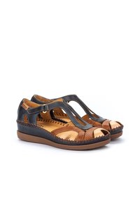 Sandales en cuir marron et marine avec un bout ouvert et un design à lanières en T, présentant des découpes et des coutures contrastantes le long des bords.
