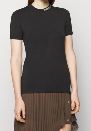 Černé tričko s krátkým rukávem se žebrovaným kulatým výstřihem a zlatým písmem. Rovný střih s hladkou texturou, doplněné plisovanou hnědou sukní.