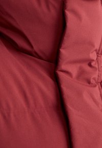Gros plan d'un tissu matelassé de couleur rouge profond avec une texture douce et rembourrée.