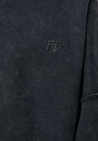 Schwarzer Hoodie mit strukturiertem Finish, mit einem dezenten, eingeprägten "ADR"-Logo auf der linken Seite und einem schlichten Rundhalsausschnitt.