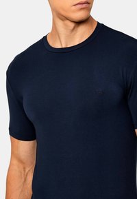 T-shirt a maniche corte di colore blu navy realizzato in cotone morbido, con scollatura rotonda e un piccolo logo sul petto.