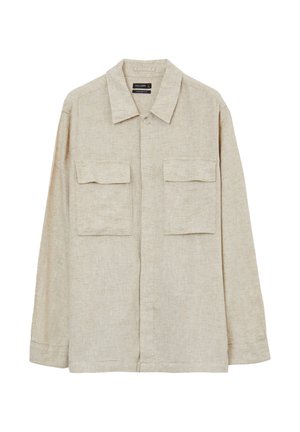 Chemise en lin beige avec col, manches longues, deux poches avant et fermeture boutonnée. Possède une coupe décontractée et une texture subtile.