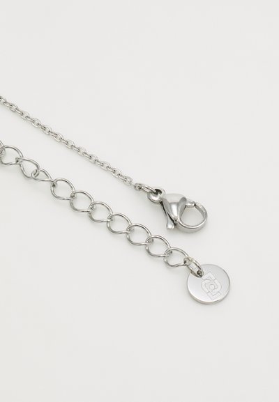 Chaîne en métal argenté avec des maillons ovales, un fermoir à mousqueton et un pendentif rond avec un design en relief. Texture lisse, design minimaliste.