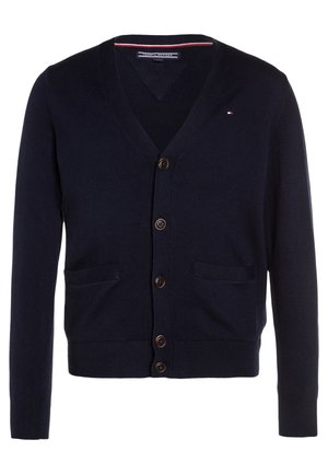 Mørkeblå V-hals cardigan med fem brune knapper, to forlommer og et lille rødt, hvidt og blåt logo på venstre bryst.