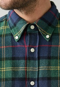 Grøn, marineblå og rød plaid skjorte med knap-up og spids krave samt hvide knapper. Stoffet har en blød, struktureret finish.