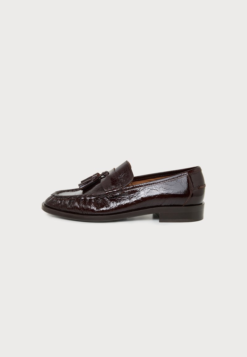 Mocassin en cuir brun foncé brillant avec pompons, talon bas et détails cousus, montré de côté extérieur sur fond uni.