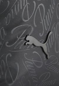Tissu texturé gris avec un motif du mot "Puma" et un logo Puma gris en position de saut bien visible.