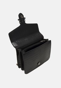 Černá peněženka s krokodýlí texturou a zacvakávacím uzávěrem. Obsahuje několik přihrádek a zipovou sekci pro bezpečné uložení.