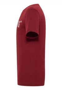 Burgundy cotton t-shirt with short sleeves, crew neck, and white logo detail on the front. Smooth texture and standard fit.