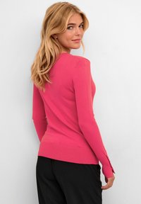 Fitted roze sweater met lange mouwen, geribbelde zoom en zijsplitten. Gemaakt van een zachte gebreide stof, met een gladde textuur en een levendige kleur.