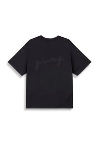 Camiseta negra de manga corta con un corte relajado, que presenta un texto bordado tonal "grmy" en la parte posterior. El tejido parece suave y liso.