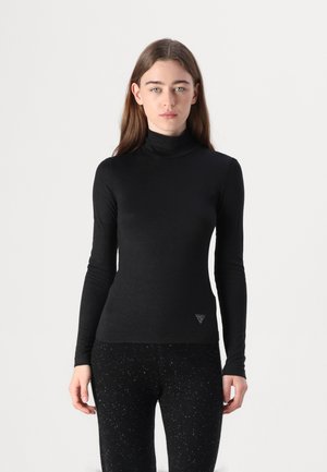 Chandail à col roulé noir à manches longues en tissu doux, avec une coupe ajustée et un logo triangulaire discret dans le coin inférieur droit.