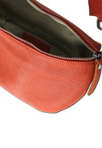 Middelgrote oranje leren schoudertas met een gestructureerde afwerking, voorzien van een zilveren ritsluiting en een afneembare schouderband. Interieurzakken zichtbaar.