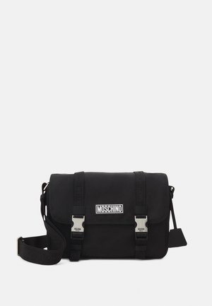 Zwarte boodschappentas van duurzaam nylon, met zilverkleurige hardware, een verstelbare riem en een Moschino-logo aan de voorkant. Twee gespsluitingen.