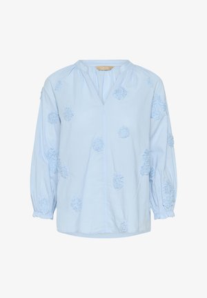 Helehall sinine puuvillane pluus, millel on V-kaelus, õhuke varrukad ja tekstureeritud lillemustriga detailid. Lõdvestunud lõige koos kogutud detailidega.