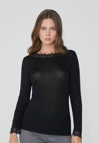 Schwarzes Langarmoberteil mit einem mit Spitze verzierten Ausschnitt und Bündchen, aus einem leichten, leicht durchsichtigen Stoff gefertigt. Eng anliegendes Design, glatte Textur.